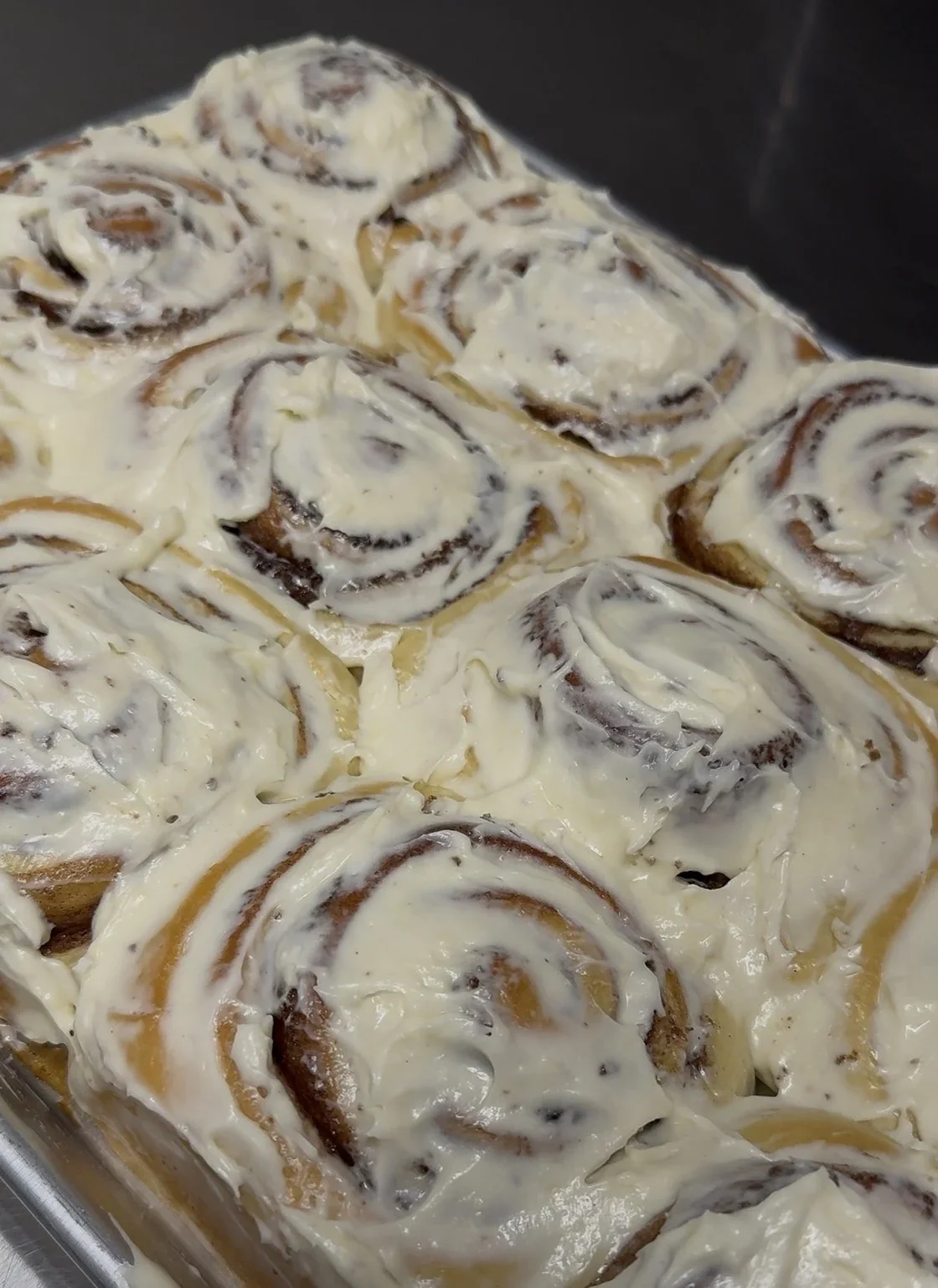 Fresh cinnamon rolls topped with cream cheese frosting at Mario’s Baking Co.
